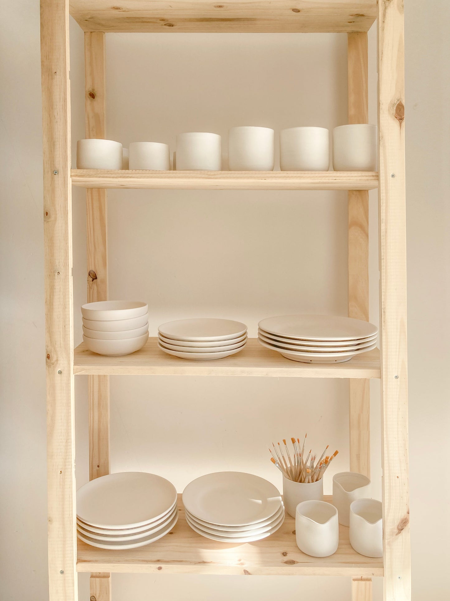 Atelier céramique à Uzès – étagère en bois avec bols, assiettes et tasses en faïence artisanale