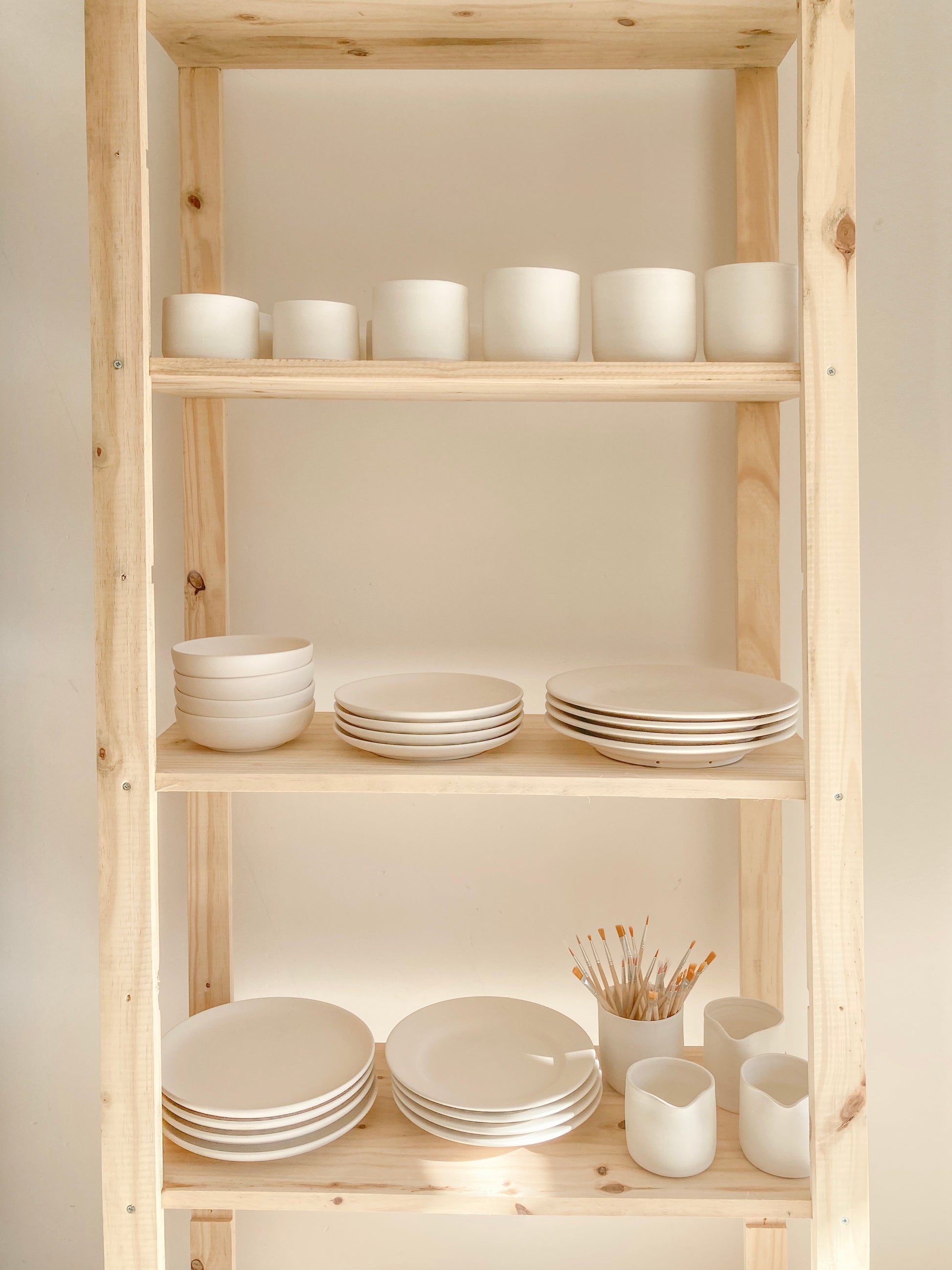 Atelier céramique à Uzès – étagère en bois avec bols, assiettes et tasses en faïence artisanale