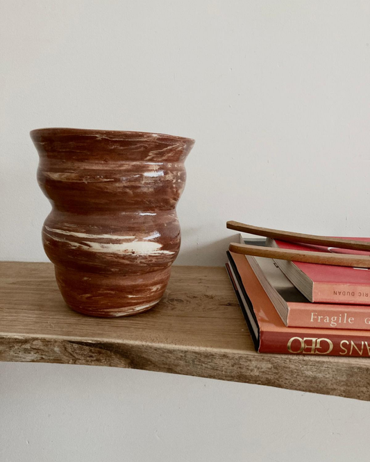 Vase ondulé terracotta marbré crème, intérieur du vase, finition brillante, posé sur étagère en bois. 