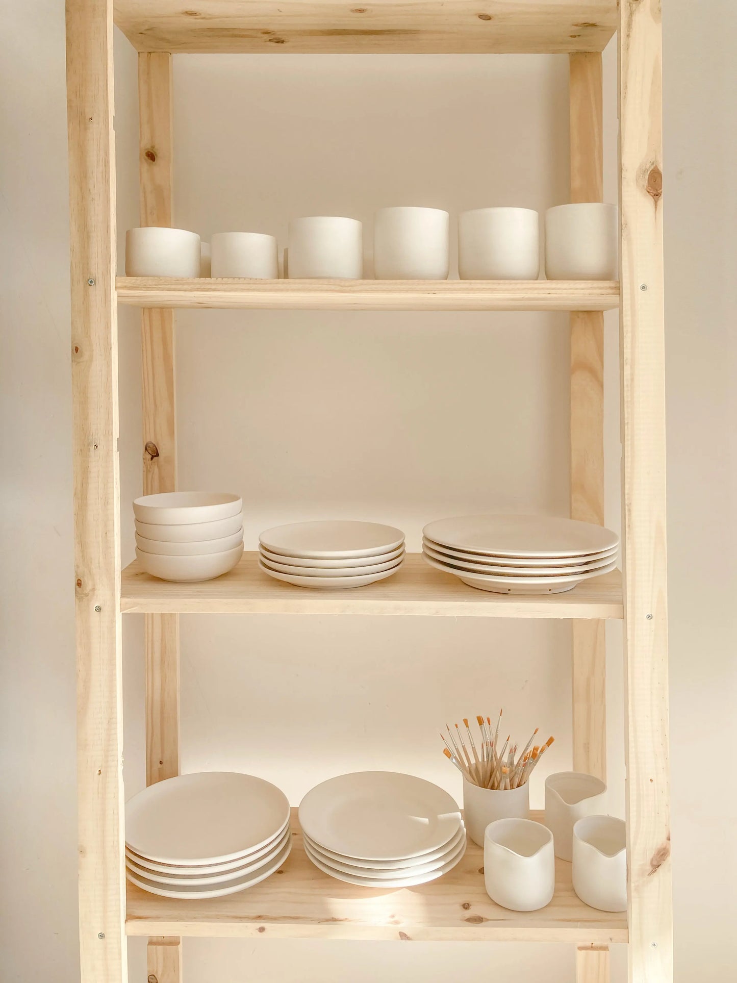Atelier céramique à Uzès – étagère en bois avec bols, assiettes et tasses en faïence artisanale